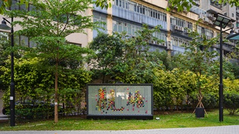 The flourishing nature’s shades of green colour contrasts with the art installation and the tightly packed buildings in the background, where the park offers the neighbourhood an escape from the urban jungle.